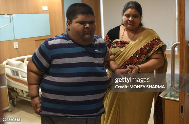 Obese Indian teen Meher Jain with his mother Pooja Jain walk in his hospital room in New Delhi on July 6, 2018. - Meher underwent a successful...