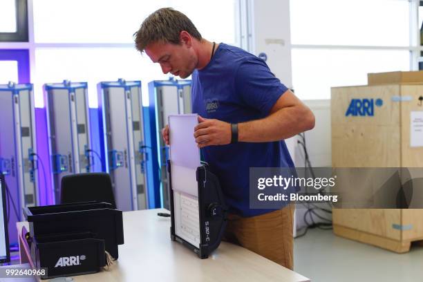 An employee inserts a light diffuser screen onto a SkyPanel light-emitting diode light at the ARRI AG cinematic and television lighting factory in...