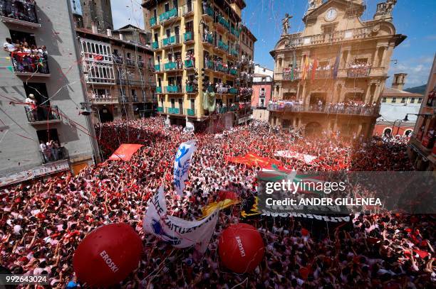 Participants hold red scarves as they celebrate the 'Chupinazo' to mark the kickoff at noon sharp of the San Fermin Festival, in front of the Town...