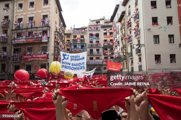 Participants hold red scarves as they celebrate the 'Chupinazo' to mark the kickoff at noon sharp of the San Fermin Festival, in front of the Town...