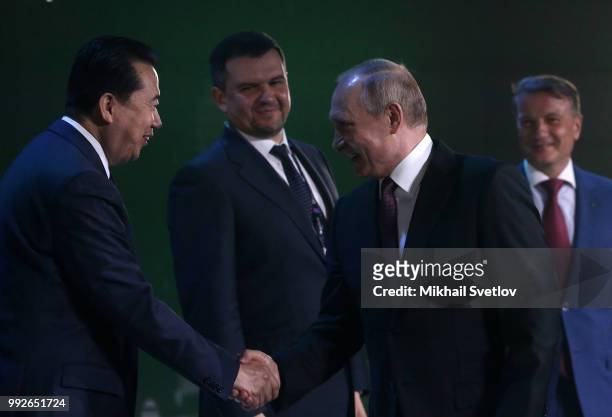 Russian President Vladimir Putin shakes hands with Interpol Director Meng Hongwei as Deputy Prime Minister Igor Akimov and CEO and Charman of...