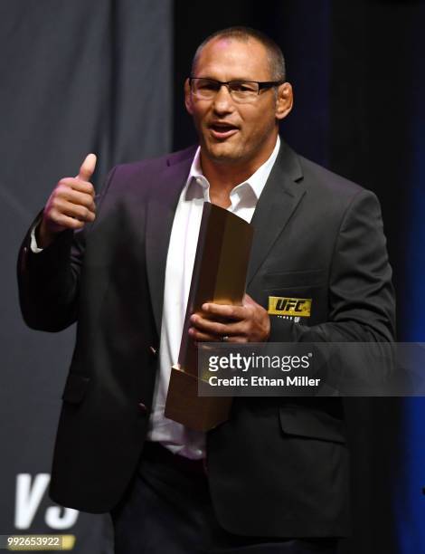 Former mixed martial artist Dan Henderson holds a trophy onstage after his 2011 fight against Mauricio "Shogun" Rua in UFC 139 was inducted into the...
