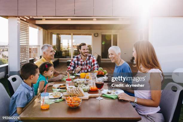 feliz extendida familia hablar durante el almuerzo en el balcón. - penthouse girl fotografías e imágenes de stock