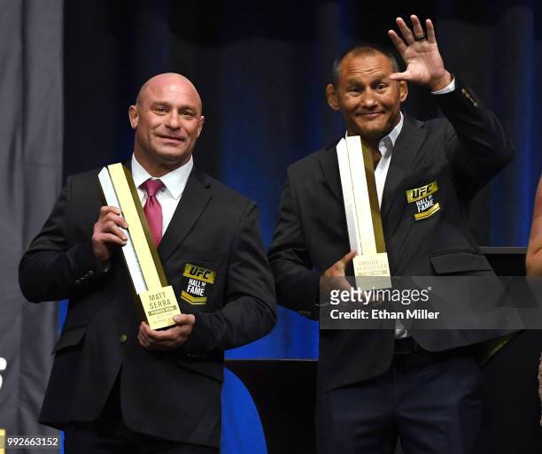 Former mixed martial artists Matt Serra and Dan Henderson pose onstage with trophies at the end of the UFC Hall of Fame's class of 2018 induction...