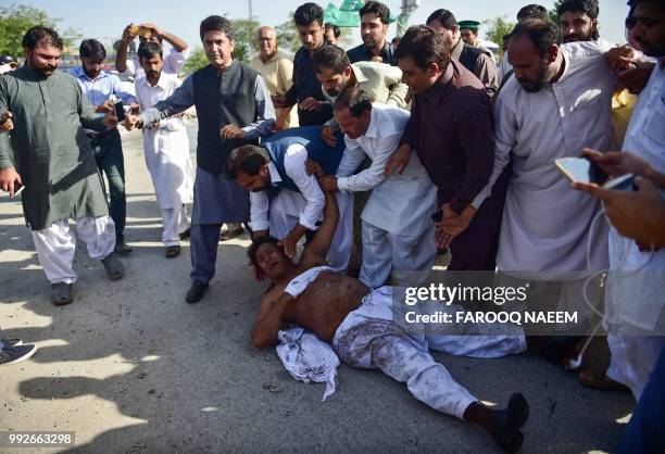 An activist of the Pakistan Muslim League-Nawaz rolls on the ground after ripping off his shirt and throwing dirt and trash over himself as other...