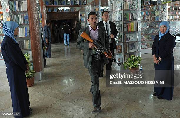 An Afghan security personel walks with his weapon in the Naser Khusro Balkhi Library during an opening ceremony in Kabul on June 6, 2011. The Naser...