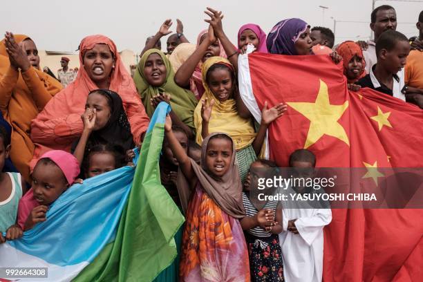 People hold Chinese and Djiboutian national flags as they wait for the arrival of Djibouti's President Ismail Omar Guellehas before the launching...