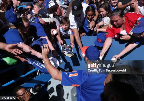 Jose Bautista of the New York Mets signs autographs for fans before the start of MLB game action against the Toronto Blue Jays at Rogers Centre on...