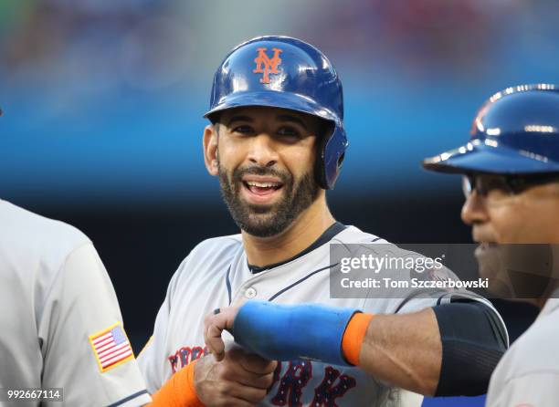 Jose Bautista of the New York Mets smiles as he stands on first base after drawing a walk and waits during a pitching change in the fifth inning...