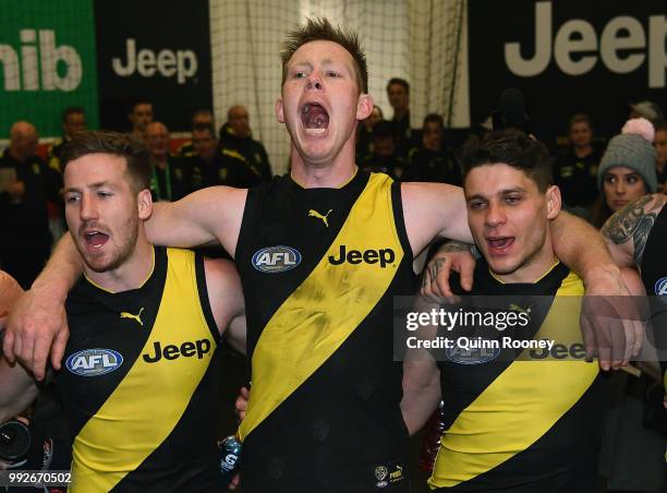 Kane Lambert, Jack Riewoldt and Dion Prestia of the Tigers sing the song in the rooms after winning the round 16 AFL match between the Richmond...