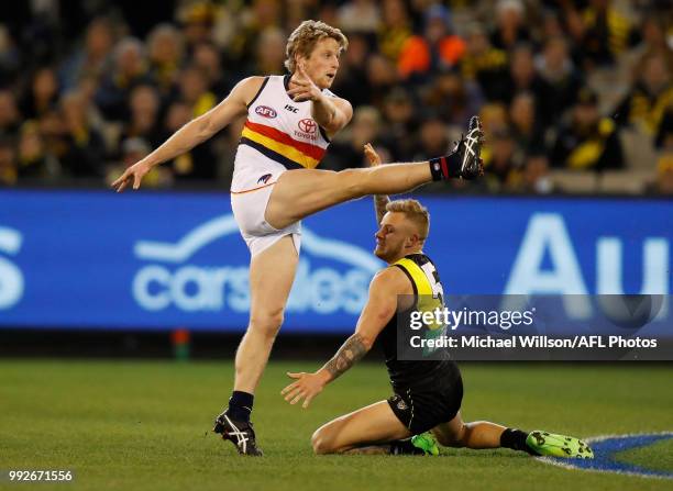 Rory Sloane of the Crows kicks as Brandon Ellis of the Tigers attempts a block during the 2018 AFL round 16 match between the Richmond Tigers and the...