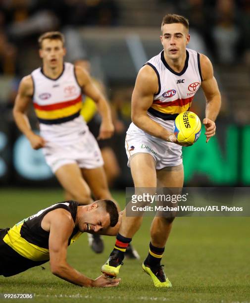 Myles Poholke of the Crows is tackled by Jack Graham of the Tigers during the 2018 AFL round 16 match between the Richmond Tigers and the Adelaide...