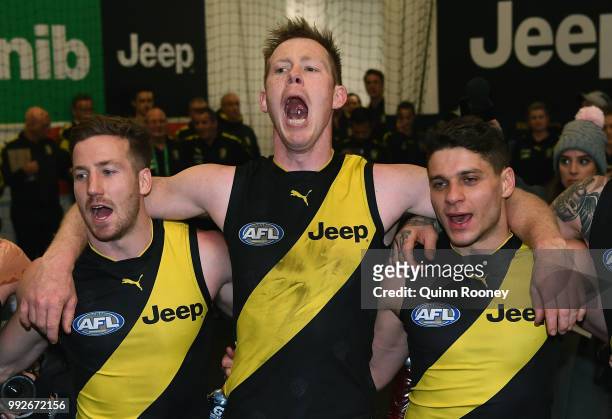 Kane Lambert, Jack Riewoldt and Dion Prestia of the Tigers sing the song in the rooms after winning the round 16 AFL match between the Richmond...