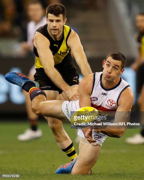 Taylor Walker of the Crows passes the ball under pressure of Trent Cotchin of the Tigers during the 2018 AFL round 16 match between the Richmond...