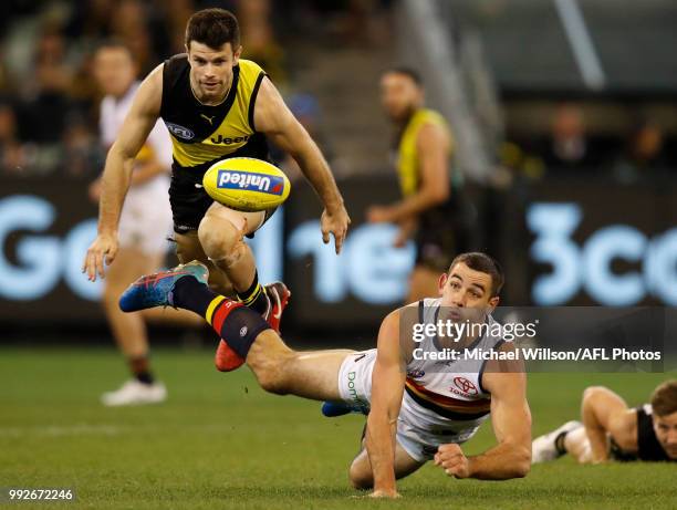 Taylor Walker of the Crows passes the ball under pressure of Trent Cotchin of the Tigers during the 2018 AFL round 16 match between the Richmond...