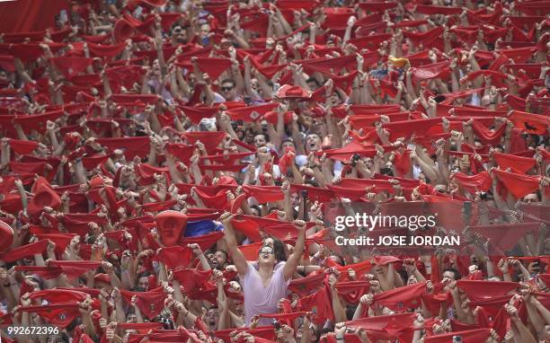 Participants hold red scarves as they celebrate the 'Chupinazo' to mark the kickoff at noon sharp of the San Fermin Festival, in front of the Town...