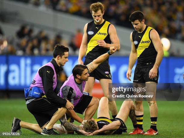 Nathan Broad of the Tigers is attended to by trainers during the round 16 AFL match between the Richmond Tigers and the Adelaide Crows at Melbourne...
