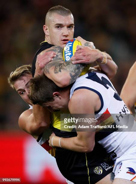 Dustin Martin of the Tigers is tackled by Daniel Talia and Matt Crouch of the Crows during the 2018 AFL round 16 match between the Richmond Tigers...