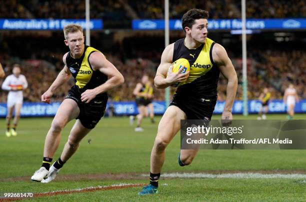 Jason Castagna of the Tigers runs with the ball ahead of Jack Riewoldt of the Tigers during the 2018 AFL round 16 match between the Richmond Tigers...