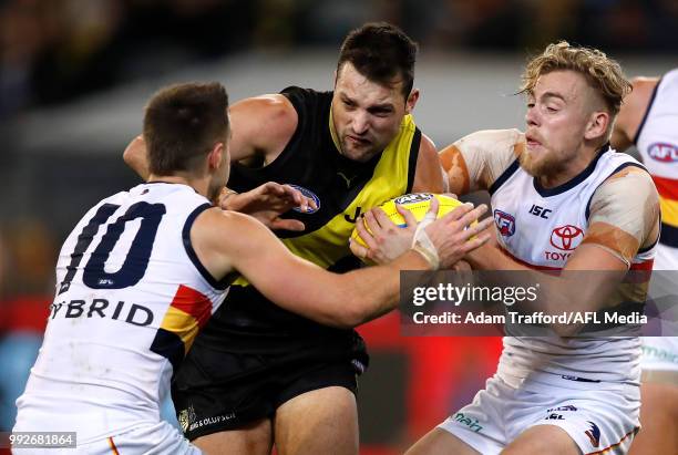 Toby Nankervis of the Tigers is tackled by Myles Poholke and Hugh Greenwood of the Crows during the 2018 AFL round 16 match between the Richmond...