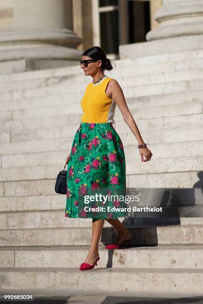 Giovanna Battaglia wears a yellow sleeveless top, a green flower print skirt, a bag, pink shoes, outside Elie Saab, during Paris Fashion Week Haute...