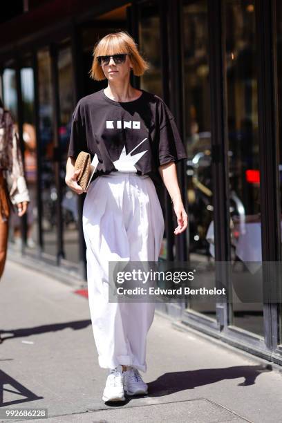 Vika Gazinskaya wears a black t-shirt, white flared pants , outside Alexis Mabille, during Paris Fashion Week Haute Couture Fall Winter 2018/2019, on...