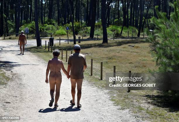 Graphic content / A naked couple walk on a path at the Arnaoutchot naturist camping on June 26, 2018 in Vielle-Saint-Girons, southwestern France. -...