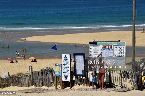Graphic content / A naked couple look at the weather forecast as they arrive at the beach of the Arnaoutchot naturist camping on June 26, 2018 in...