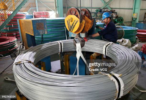 Employees process coils of steel wire at a steel factory on July 3, 2018 in Nantong, Jiangsu Province of China. According to the data released by...