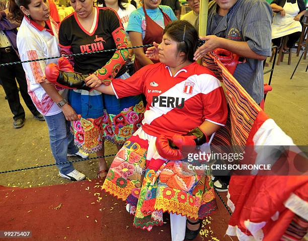 An Andean peasant woman wearing colorful skirts and T-shirts with the colors of the Peruvian flag, rests after boxing against a Bolivian Mamacha on...