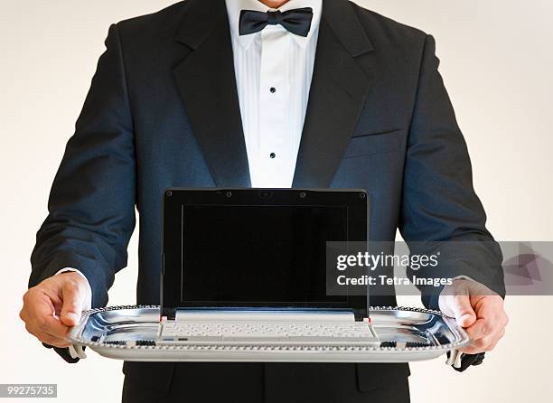 butler holding laptop on tray - laptop netbook stock pictures, royalty-free photos & images