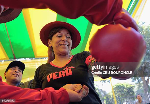 Peruvian Andean peasant , is helped with her gloves before an encounter against a Bolivian Mamacha at a boxing ring, to promote a fair of handicrafts...