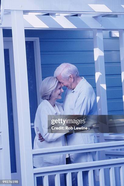 elderly couple embracing on porch - met de neus aanraken stockfoto's en -beelden