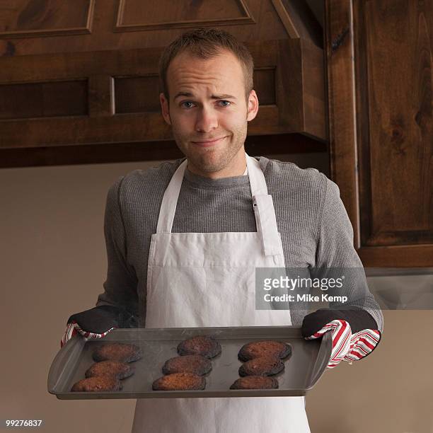 man holding tray of burnt cookies - man tray food holding stockfoto's en -beelden