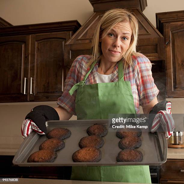 woman holding tray of burnt cookies - burnt cooking stock pictures, royalty-free photos & images