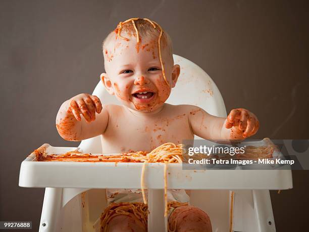 baby covered in spaghetti - baby boy getting messy eating spaghetti stock pictures, royalty-free photos & images