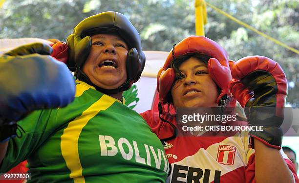 Two Andean peasant women wearing T-shirts with the colors of their national flags waves after measuring themselves at a boxing ring to promote a fair...