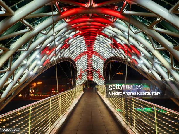 bridge of peace illuminated by night, tbilisi, georgia - ricordi stock-fotos und bilder