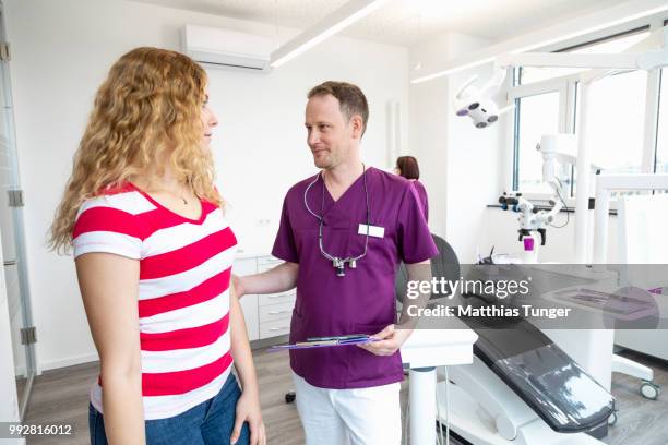 eine junge frau im gespräch mit einem zahnarzt - ficha-dentária imagens e fotografias de stock