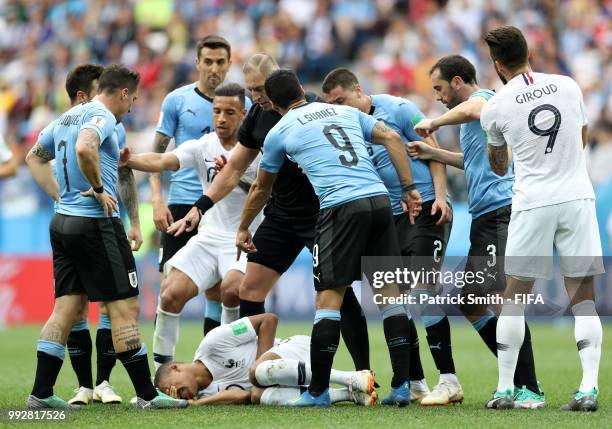 Kylian Mbappe of France lies on the pitch injured while Uruguay and France players argue during the 2018 FIFA World Cup Russia Quarter Final match...