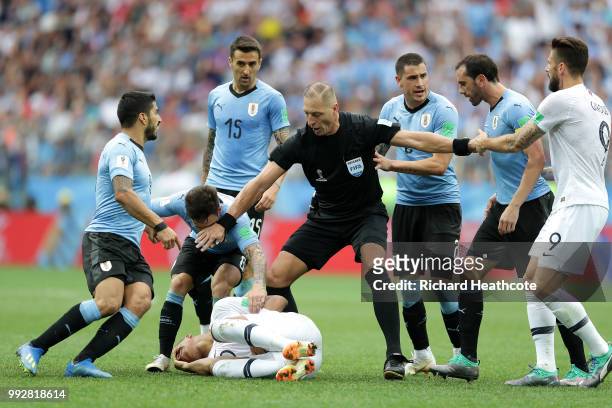 Referee Nestor Pitana stops Diego Godin, Nahitan Nandez and Luis Suarez of Uruguay from arguing with Kylian Mbappe of France during the 2018 FIFA...