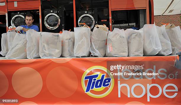 Member of the Tide's Loads Of Hope mobile laundry crew lines up a row of recently cleaned laundry at Loads of Hope Truck - Laundry Drop-Off Site:...