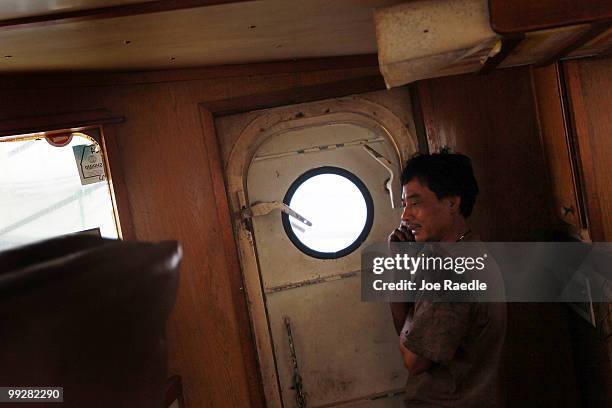 Dranson Pham talks on the cell phone as he passes time away in the shrimp boat he works on after the owner shut down operations due to the massive...