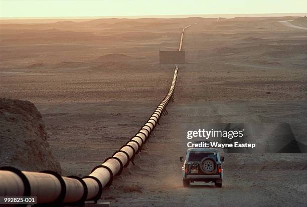 saudi arabia, main oil pipeline, car driving by at dusk - suadi arabia stockfoto's en -beelden