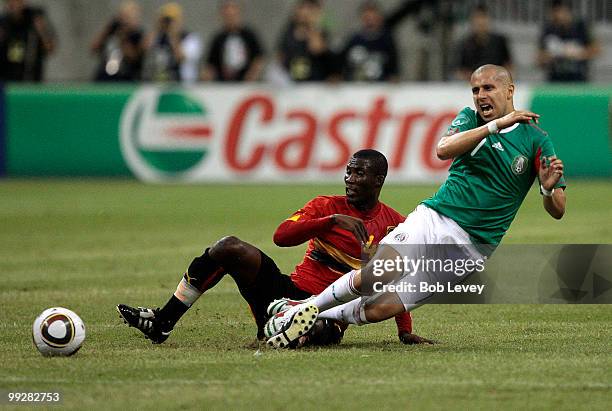 Adolfo Bautista of Mexico is brought down from behind by Francisco de Asis of Angola at Reliant Stadium on May 13, 2010 in Houston, Texas.