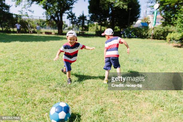 公共の公園でサッカーをしている兄弟 - 家族　日本人　走る ストックフォトと画像