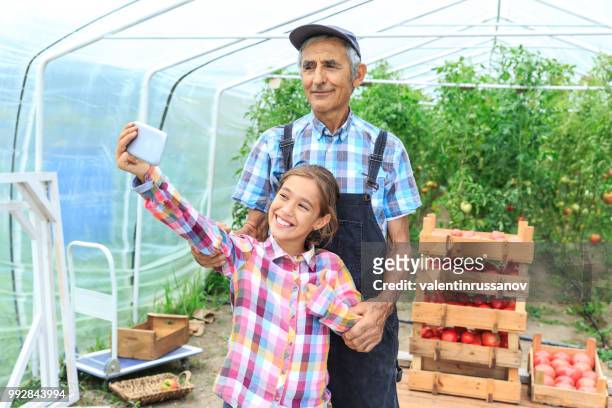 petite fille prenant selfie avec son grand-père - agriculteur selfie photos et images de collection