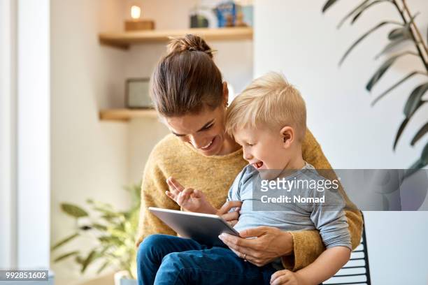 madre e figlio felici che usano il tablet digitale a casa - scandinavian home foto e immagini stock