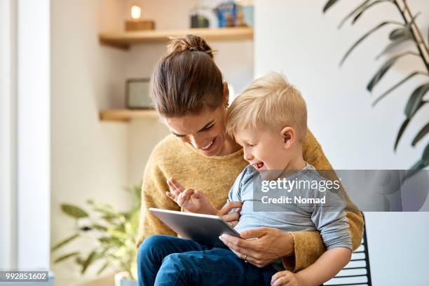 happy mother and son using digital tablet at home - scandinavian home stock pictures, royalty-free photos & images