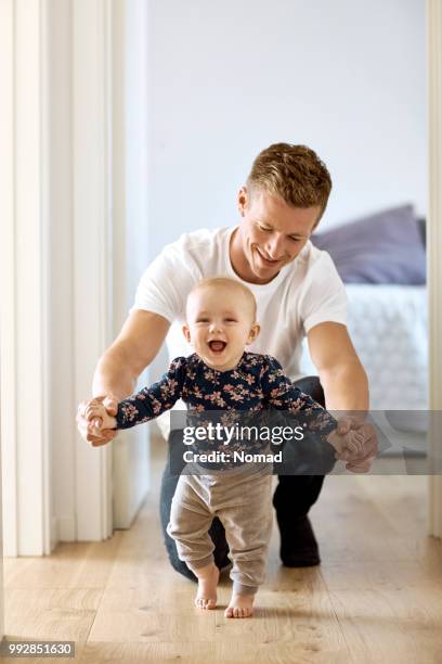 vader onderwijs zoon te lopen in gang thuis - father and baby stockfoto's en -beelden